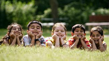 Image of children resting chins on elbows, grinning.