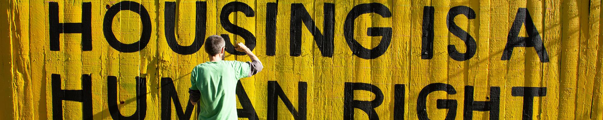 Housing is a human right sign being painted on fence 